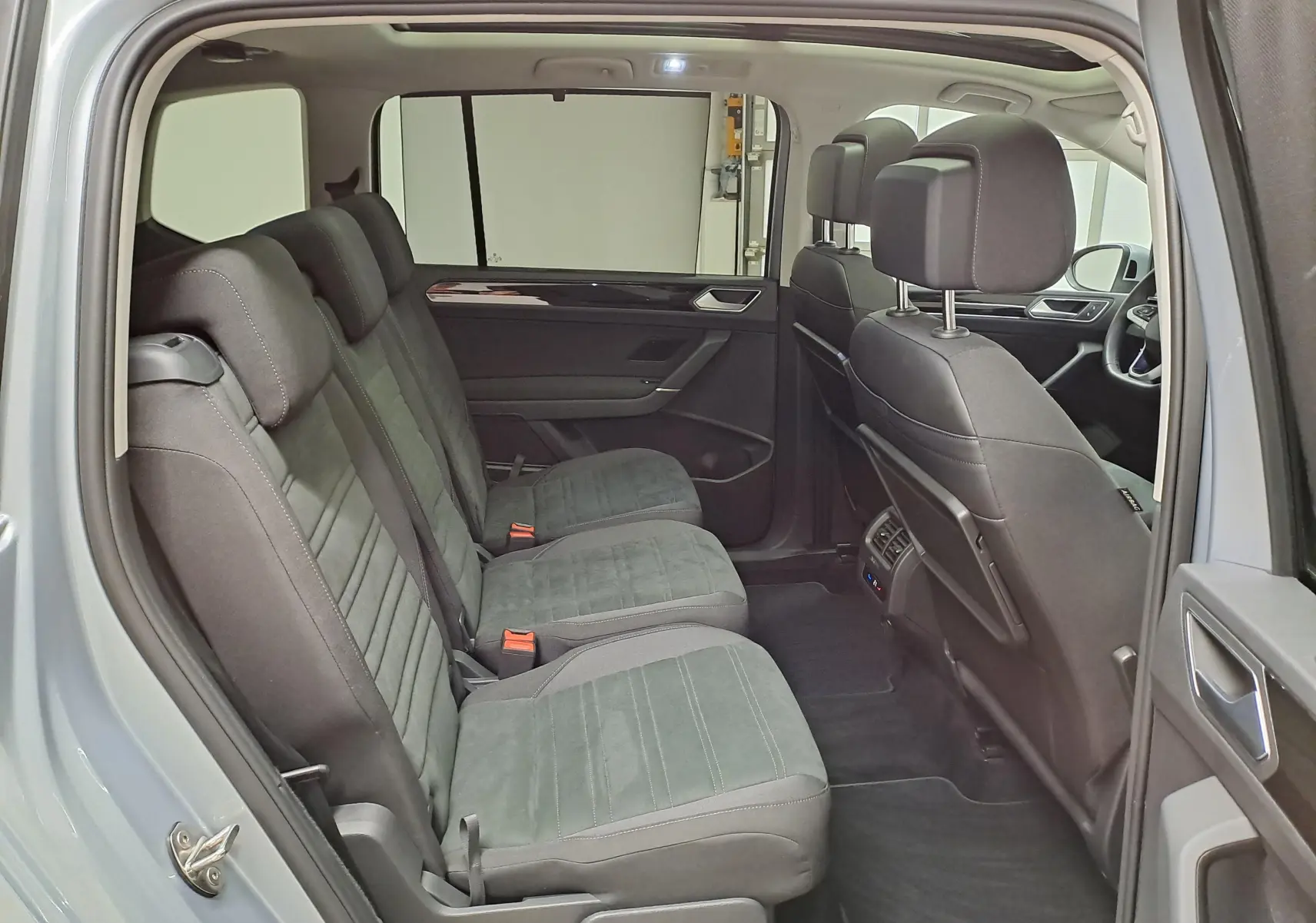 Vue intérieure côté gauche montrant la deuxième rangée de sièges en tissu gris du Volkswagen Touran 2025 gris argent.