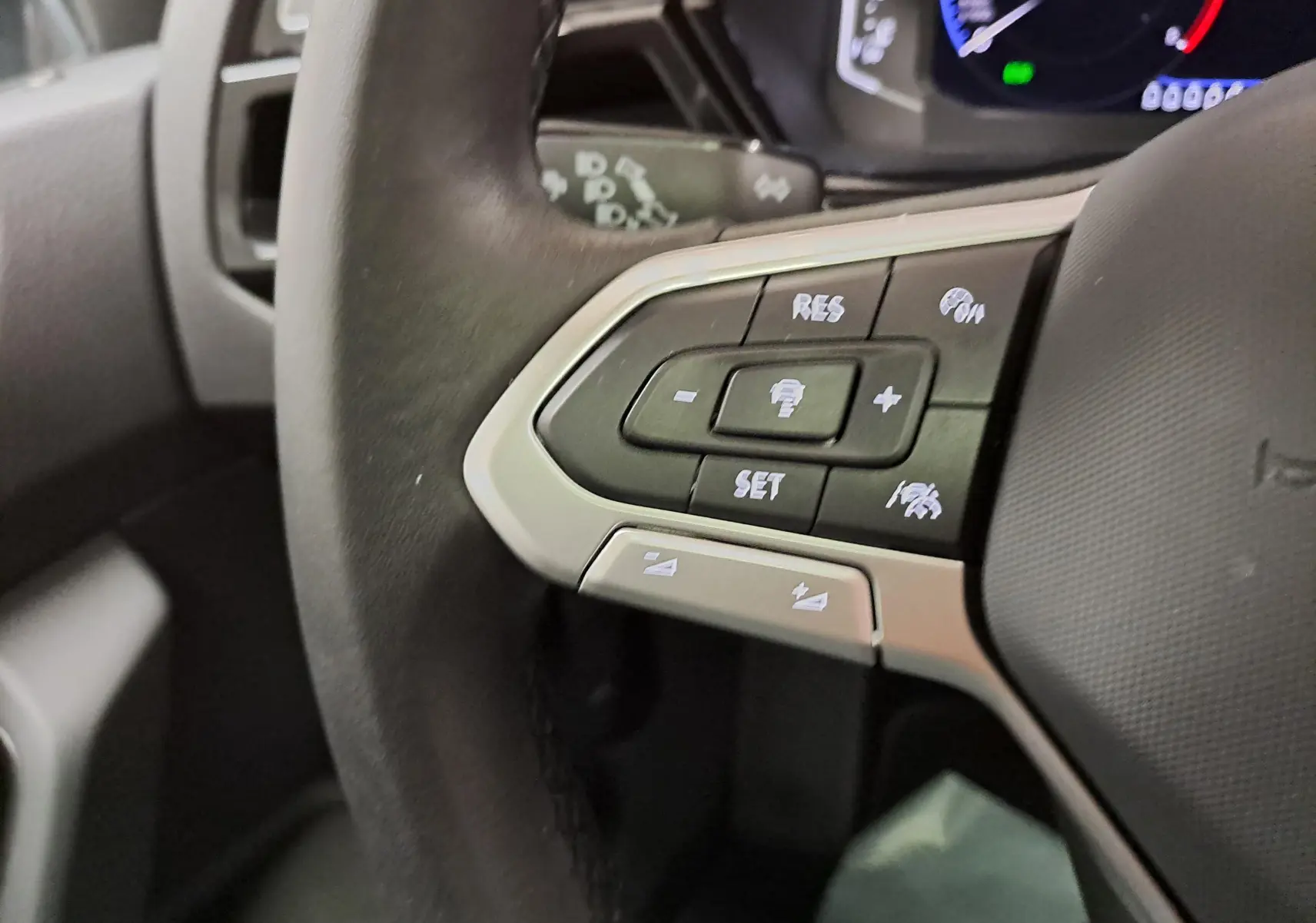 Gros plan sur les commandes au volant à gauche du Volkswagen Touran 2025, soulignant les boutons du régulateur et assistant de conduite.