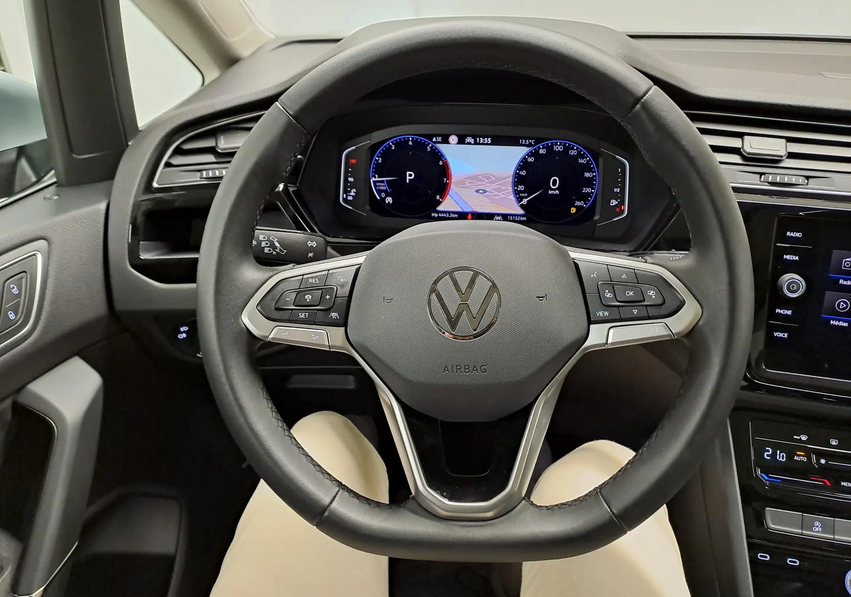 Vue 3/4 avant droit d'un Volkswagen Touran gris argent avec toit ouvrant panoramique en intérieur showroom.