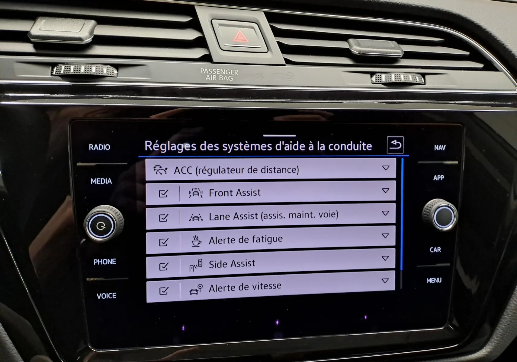 Écran tactile central du Volkswagen Touran 2025 affichant les réglages des aides à la conduite, avec commandes autour.