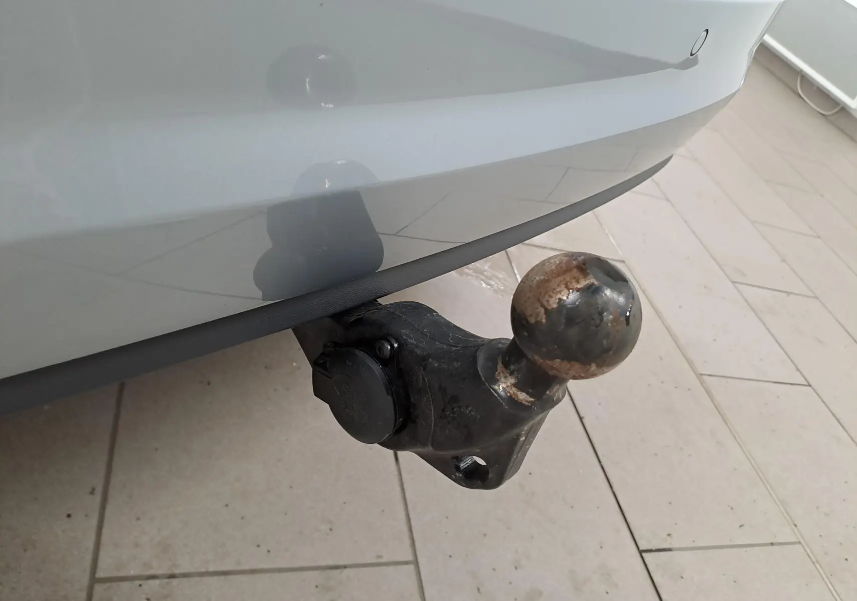 Vue arrière d'un Volkswagen Touran gris argent avec feux allumés et attelage visible dans un garage.