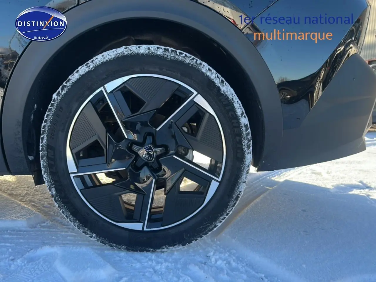 Gros plan sur la roue avant gauche noire d'une Peugeot 408 Hybrid 145 GT e-dcs6, jante alu design en hiver.