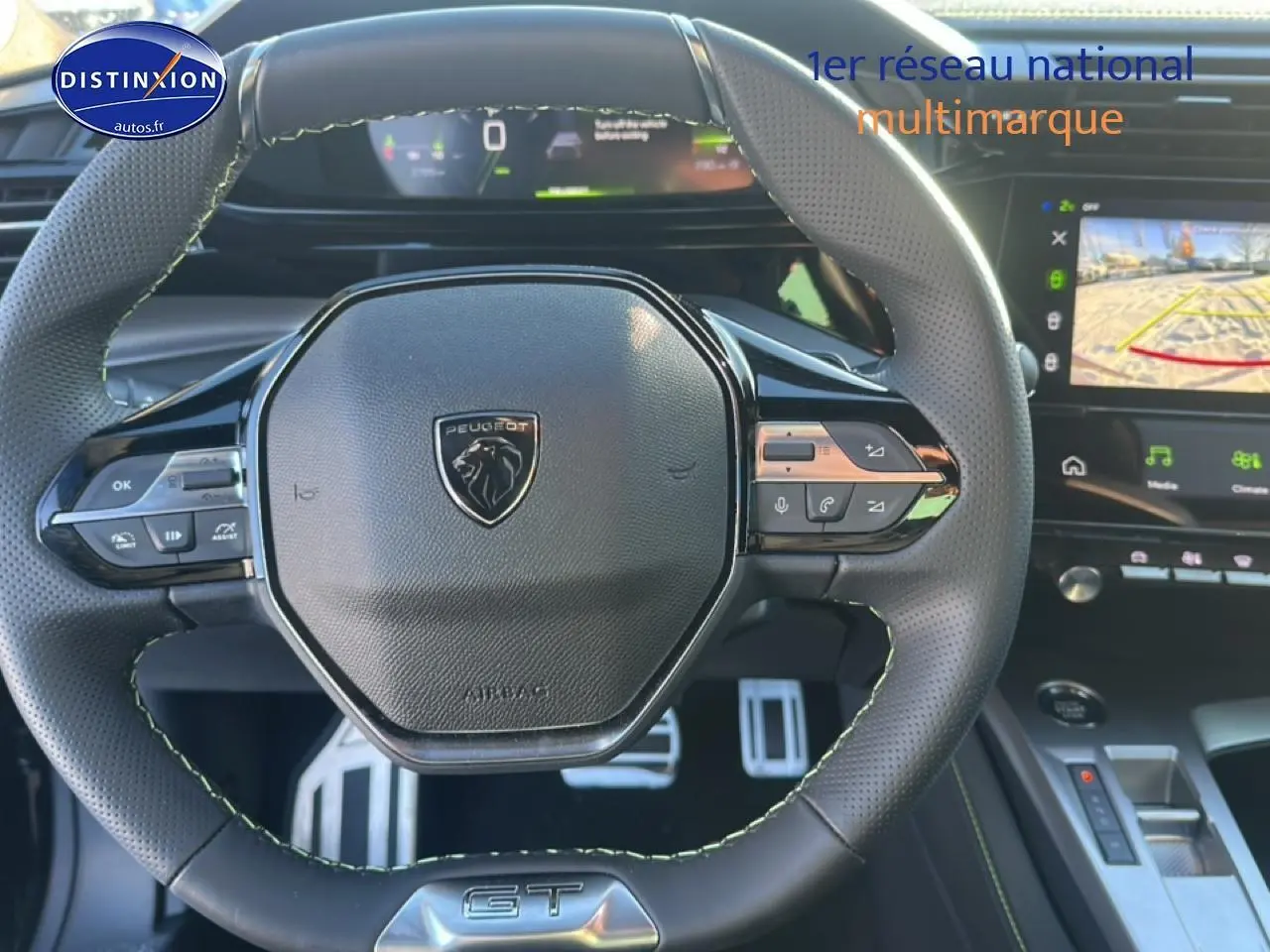 Vue rapprochée du volant cuir noir avec logo Peugeot et tableau de bord numérique de la 408 Hybrid 145 GT.