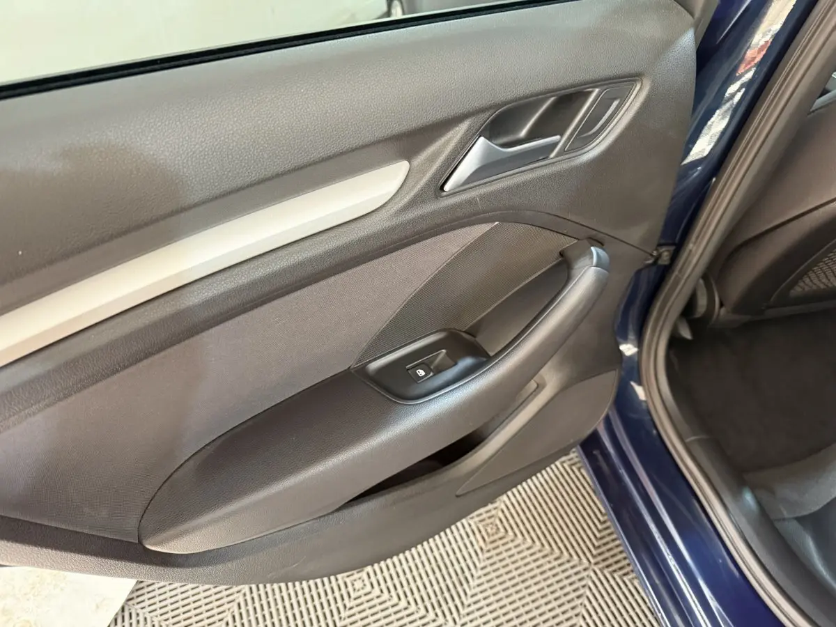 Vue rapprochée de la porte arrière droite bleu foncé d’une Audi A3 2.0 TDI 2018 avec poignée et commande de lève-vitre.