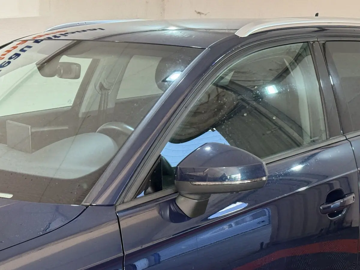 Vue rapprochée côté gauche d’une Audi A3 2.0 TDI Business Line bleu avec rétroviseur et portière visibles.