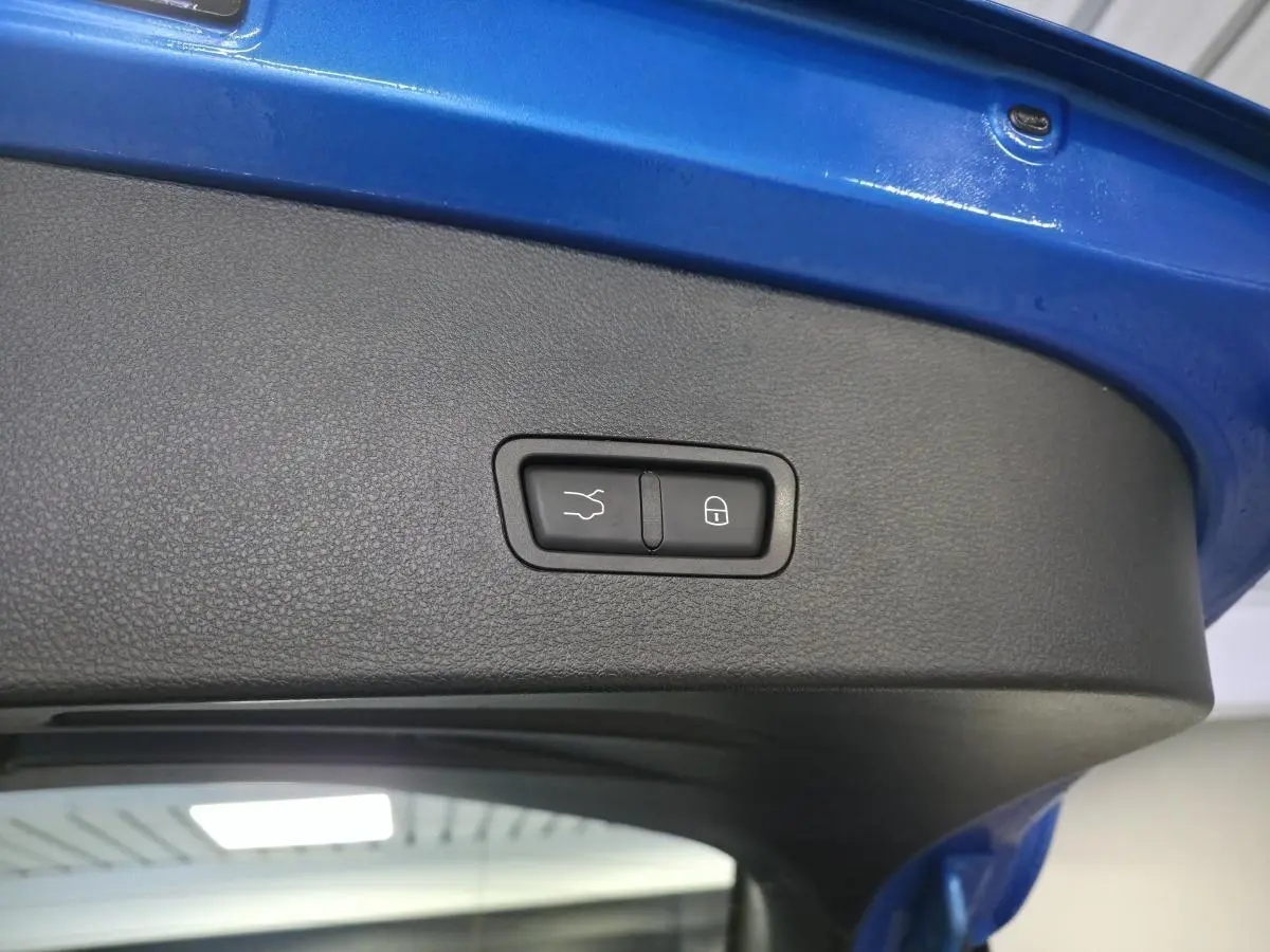 Détail du hayon électrique bleu de l'Alfa Romeo Tonale 2025 avec bouton de fermeture mains libres et verrouillage intégré.