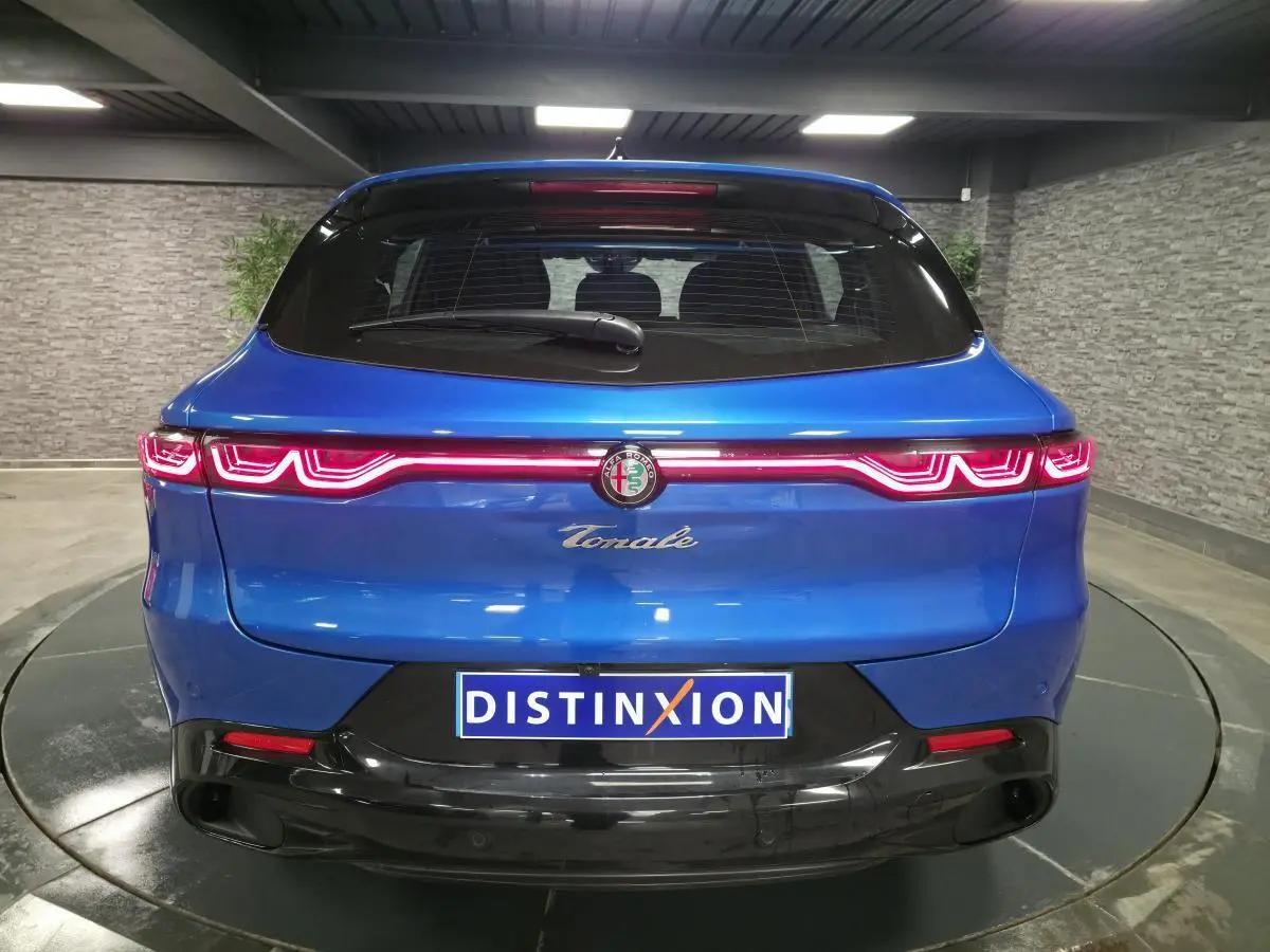 Vue arrière d'une Alfa Romeo Tonale bleu métallisé avec feux LED distinctifs et logo central dans un showroom.