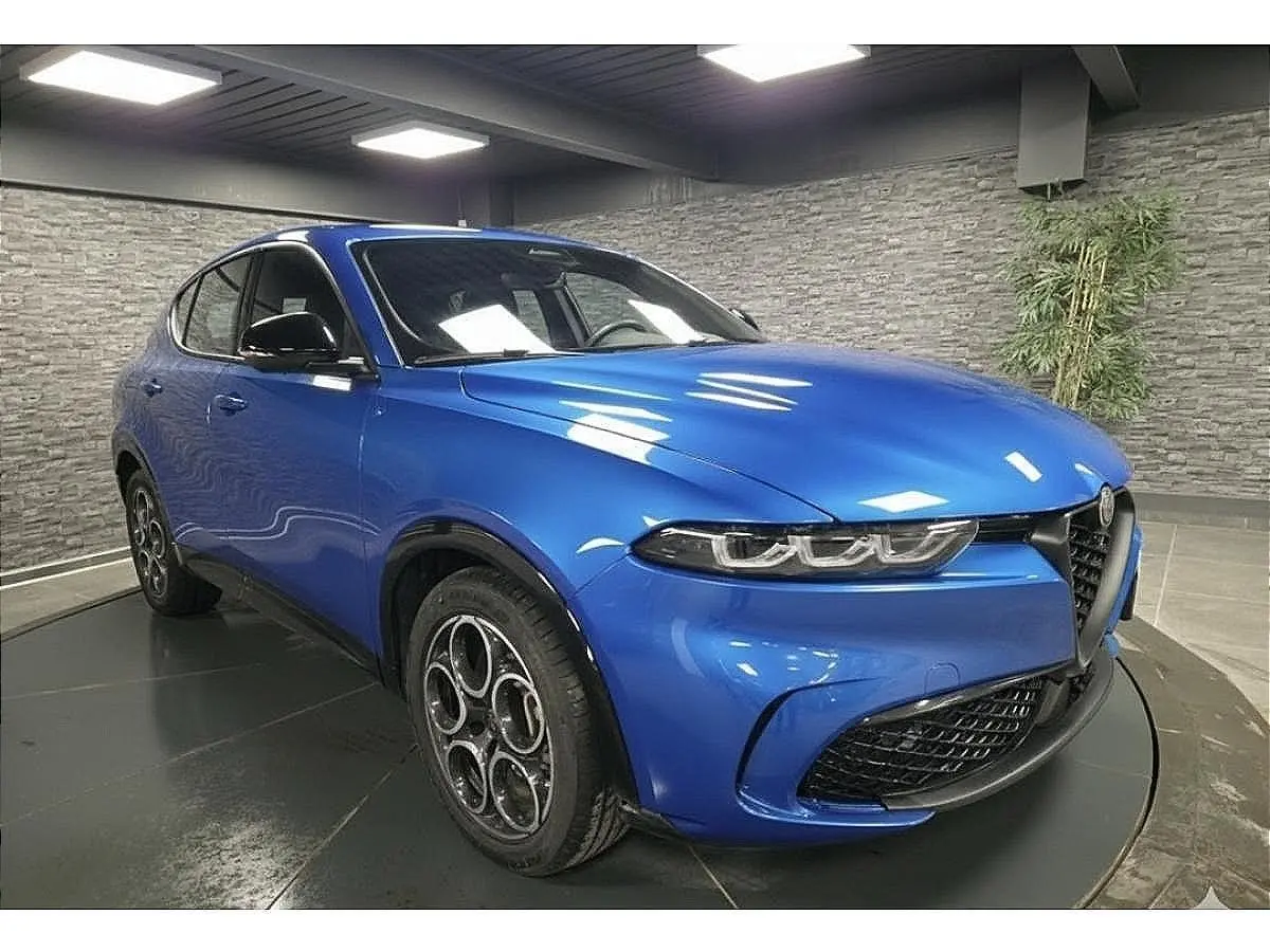 Vue 3/4 avant gauche d'un Alfa Romeo Tonale 2025 bleu métallisé avec jantes alliage et calandre noire distinctive.