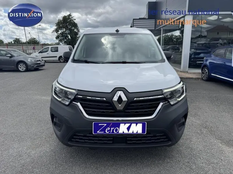Vue avant d'un Renault Kangoo Van blanc avec calandre noire et logo Renault bien visible, sur parking extérieur.