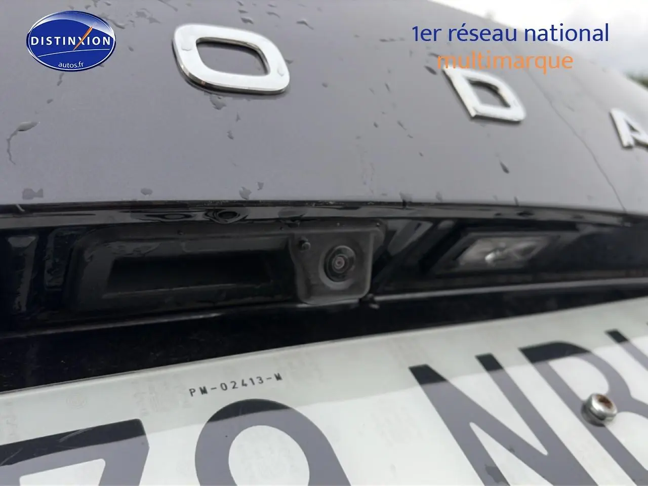 Gros plan sur la caméra de recul intégrée au hayon noir d'un Skoda Karoq 2025, avec logo partiel visible.