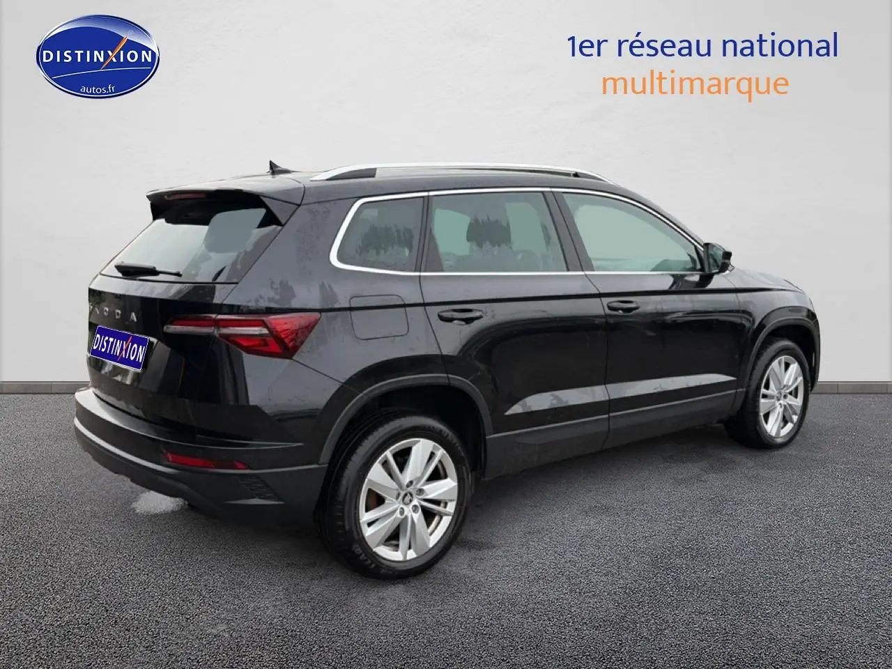 SUV Skoda Karoq noir vu de trois quarts arrière droit, avec jantes alu et barres de toit visibles.