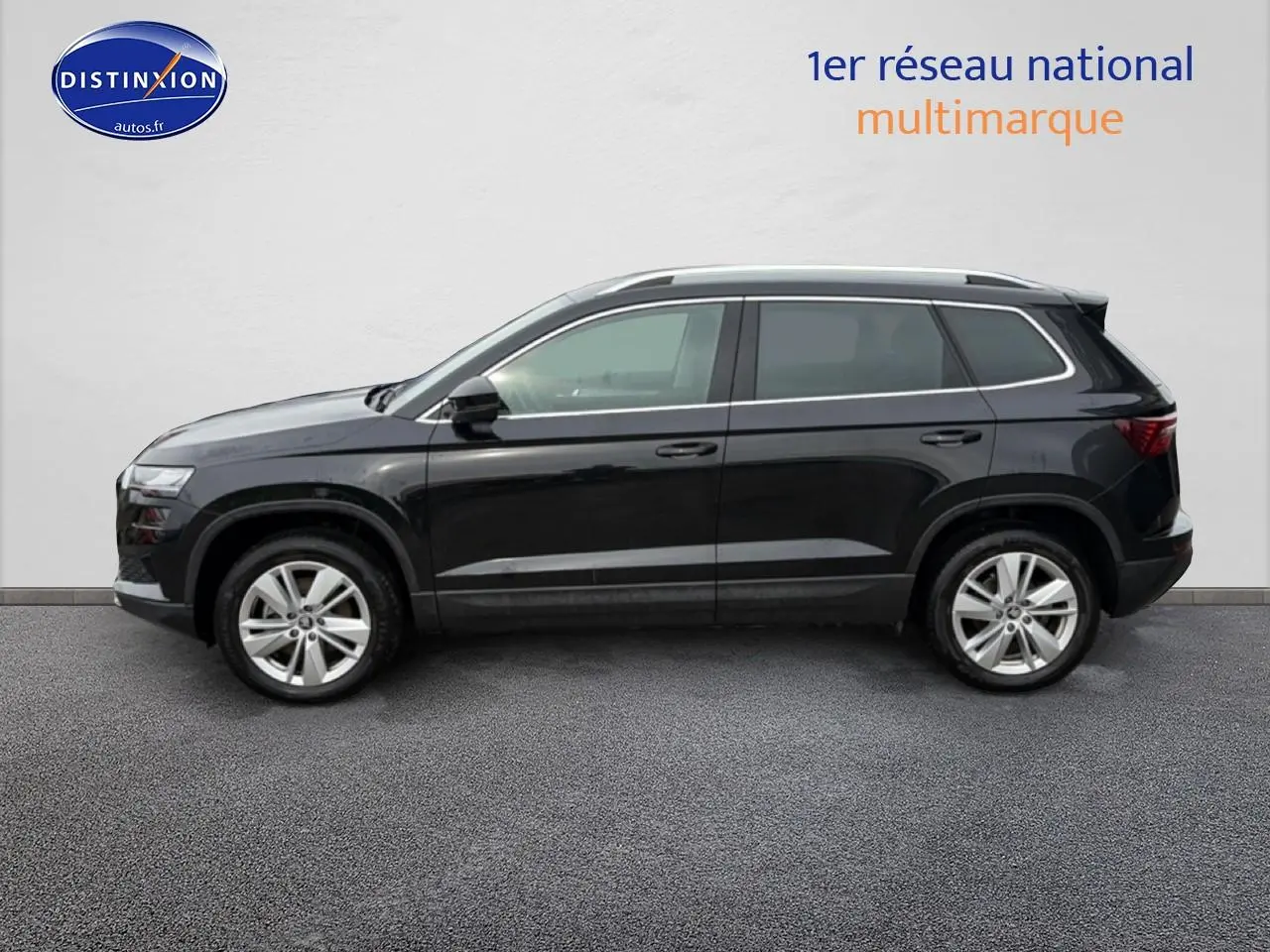 Profil droit d'un Skoda Karoq noir 2025 avec jantes alu et barres de toit visibles sur fond neutre.