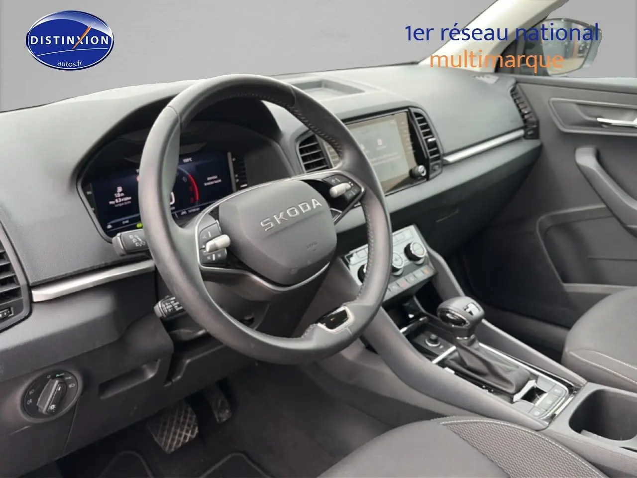 Vue intérieure du poste de conduite du Skoda Karoq noir 2025, volant cuir multifonction et écran tactile central visible.
