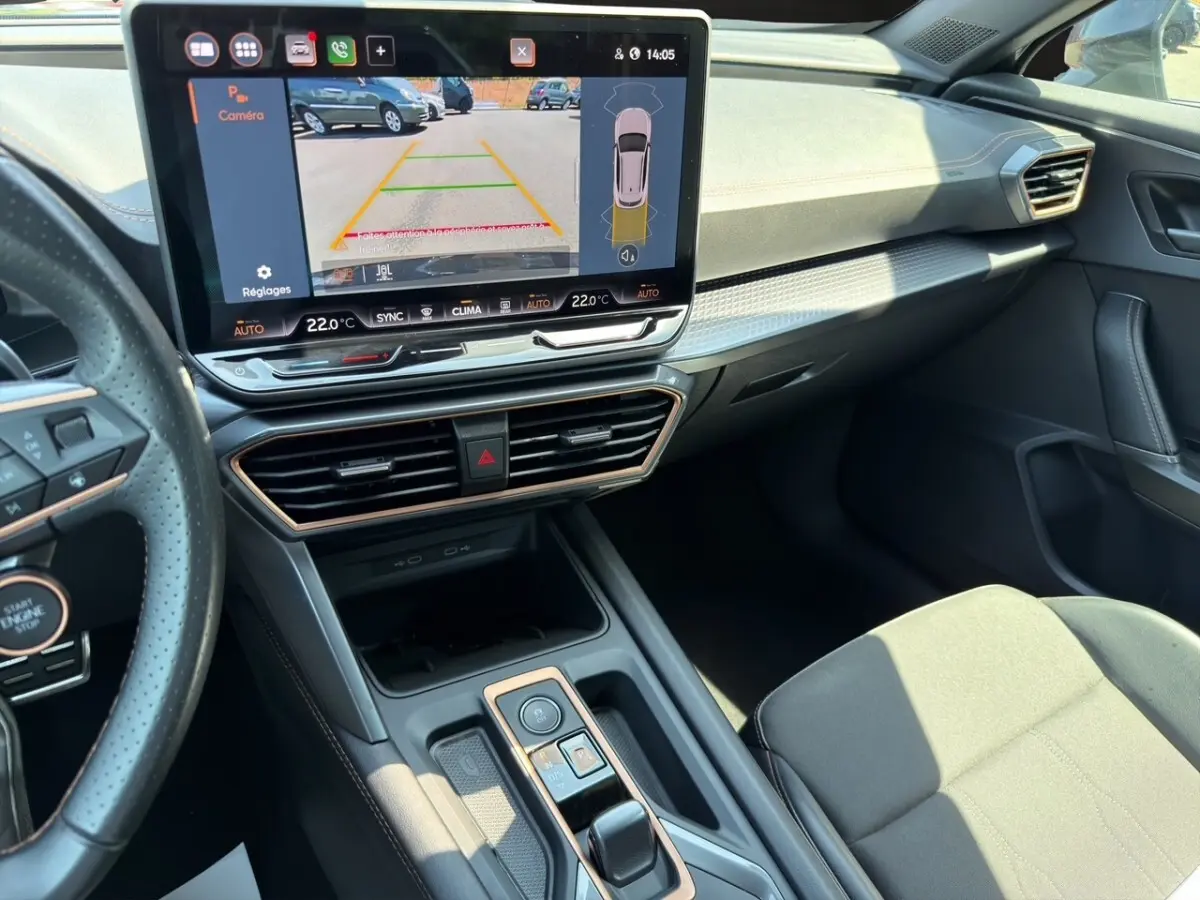 Vue intérieure côté conducteur du tableau de bord et écran tactile affichant la caméra de recul du CUPRA Formentor gris foncé.