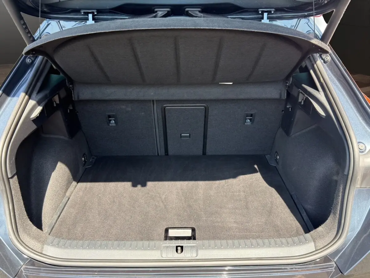 Coffre ouvert vu de l'arrière d'une CUPRA Formentor gris foncé, montrant un espace de chargement propre et spacieux.