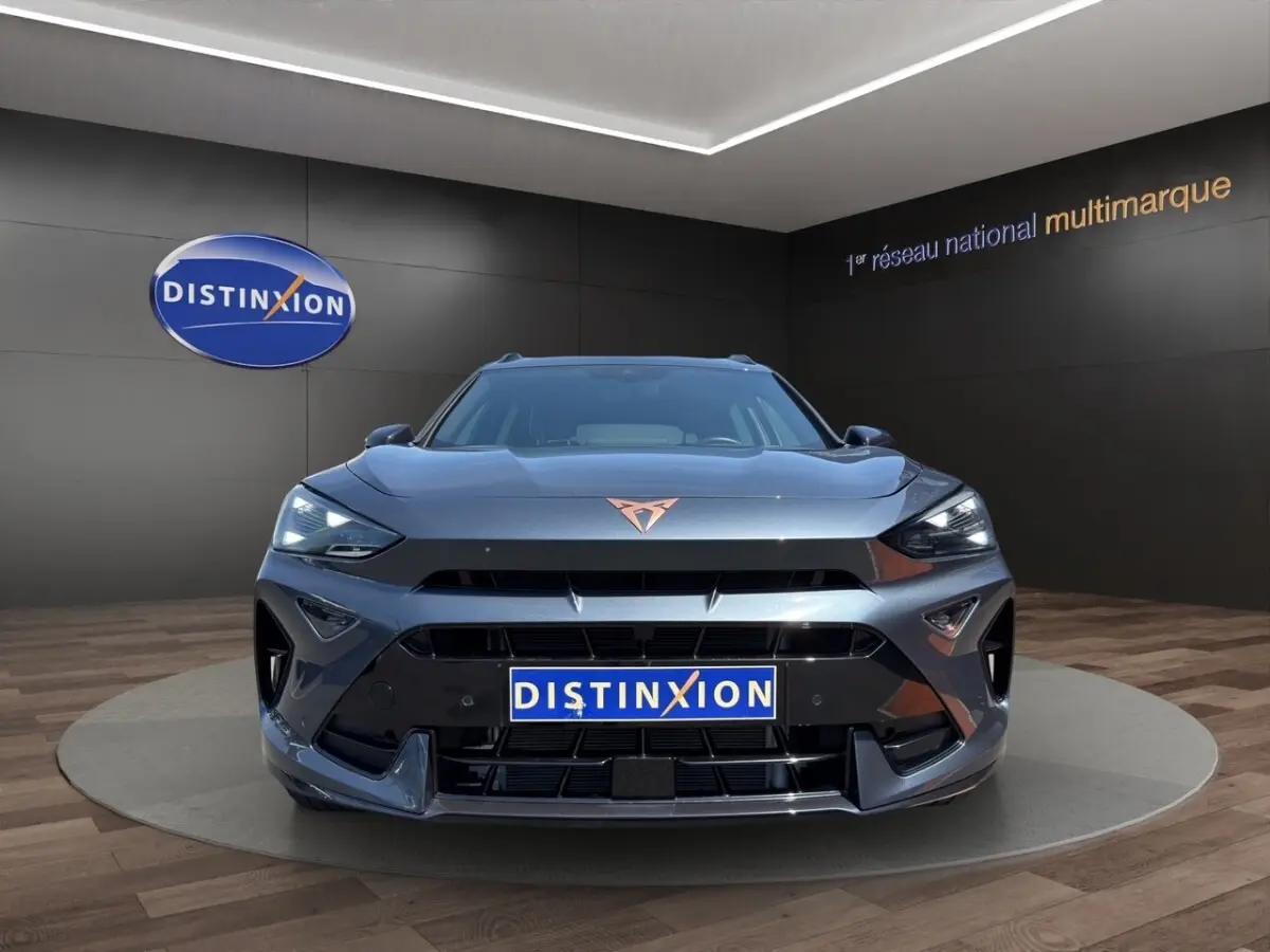 Vue avant d'un CUPRA Formentor gris foncé avec logo cuivré et phares LED allumés en showroom.