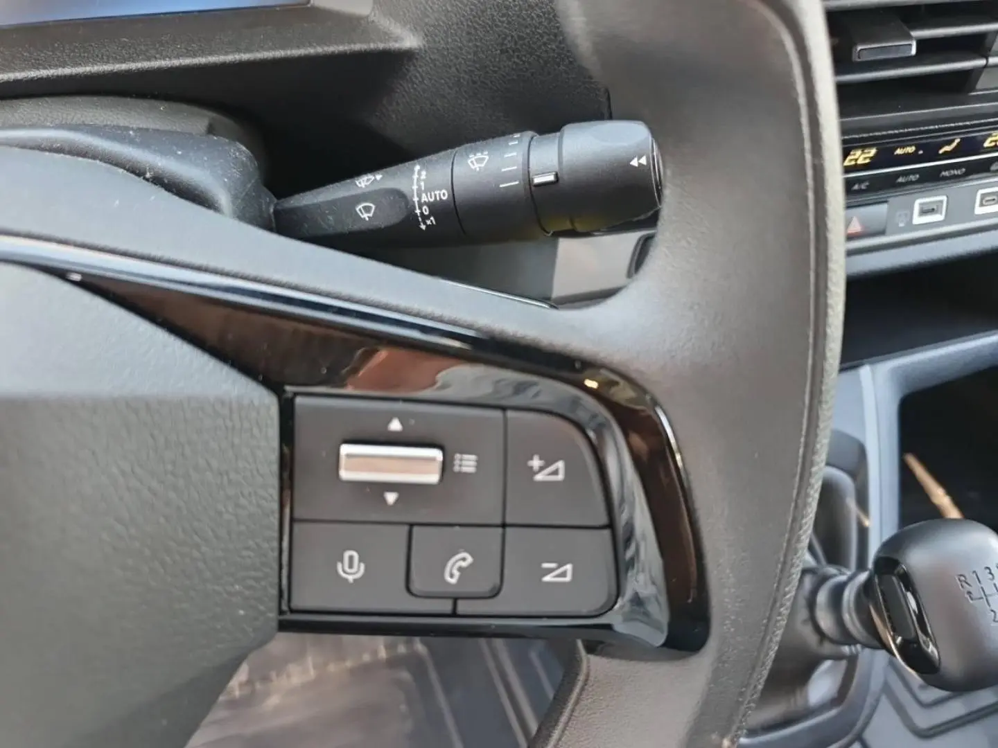 Gros plan sur les commandes au volant et levier de vitesse manuel du Toyota Proace Fourgon blanc Glacier, intérieur gris foncé.