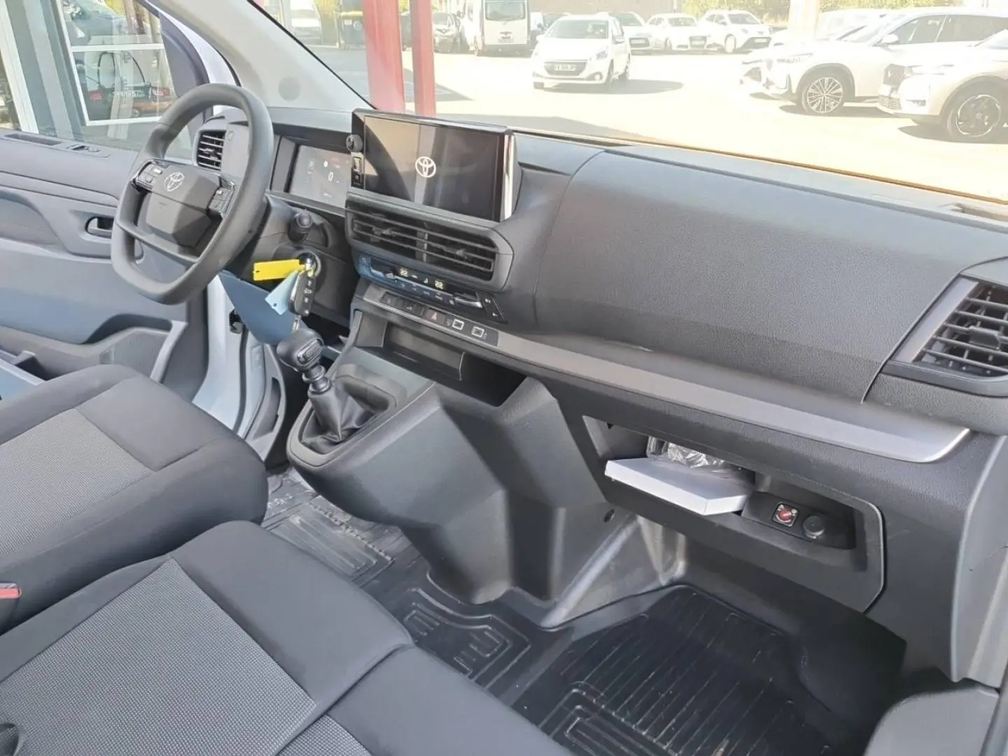 Intérieur du Toyota Proace Fourgon blanc, vue côté conducteur, tableau de bord moderne avec écran tactile et banquette 2 places.