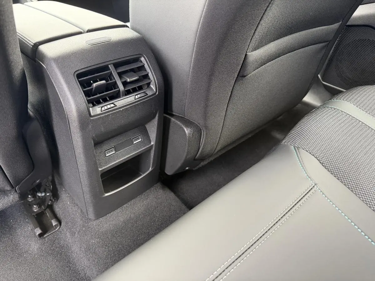 Vue rapprochée de la console arrière avec aérateurs et prises USB C, sièges gris foncé avec surpiqûres bleues Peugeot 308 SW 2024.