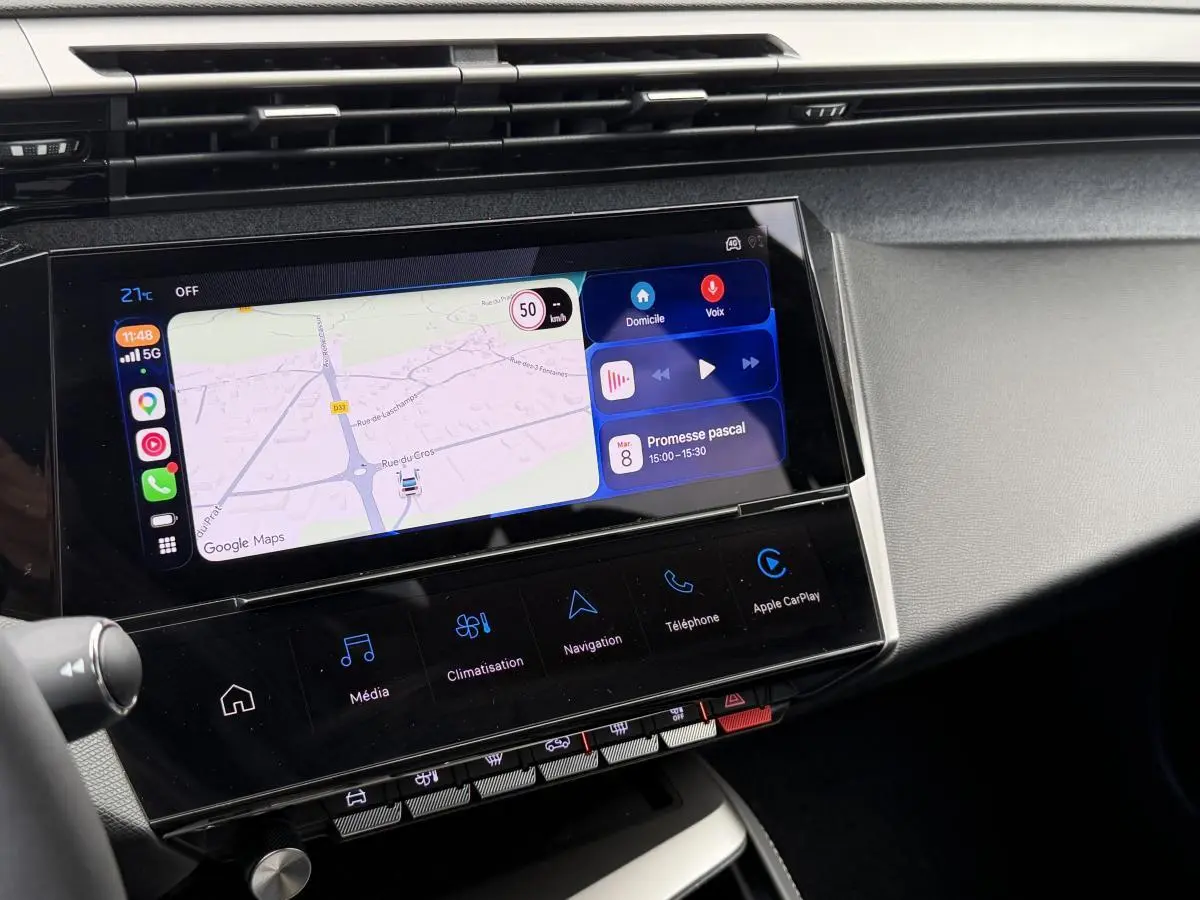 Vue rapprochée de l’écran tactile central du Peugeot 308 SW 2024 rouge, affichant la navigation et les commandes multimédias.