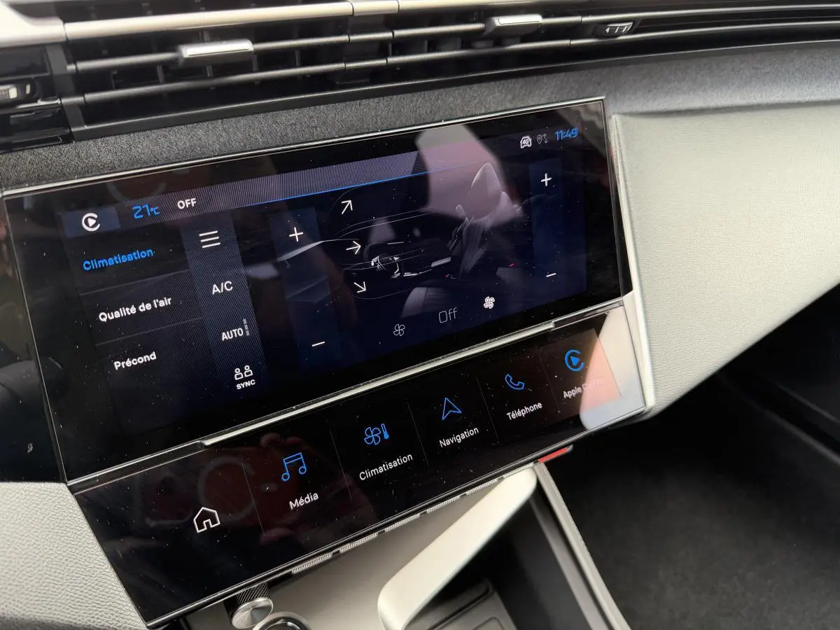 Écran tactile central de la Peugeot 308 SW 2024 en vue rapprochée, affichant les commandes de climatisation et multimédia.