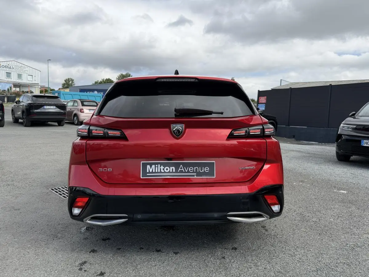 Vue arrière d’une Peugeot 308 SW hybride rouge Elixir avec feux LED et double sortie d’échappement chromée.