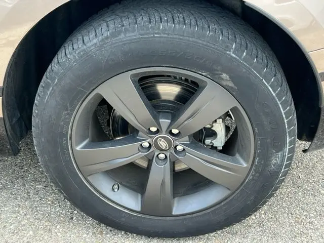 Gros plan sur la roue avant droite du Range Rover Velar marron 2018 avec jante alliage noir et logo Land Rover central.