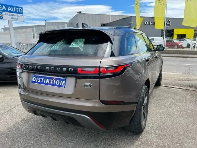 Vue 3/4 arrière d'un Range Rover Velar marron 2018 avec feux arrière fins et toit noir contrastant.