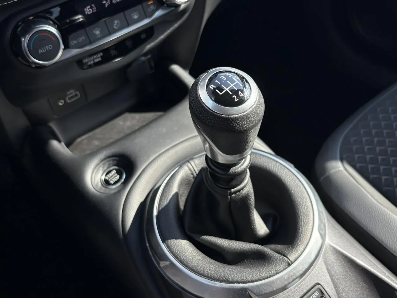 Le levier de vitesses manuel noir et argenté du Nissan Juke 2024, avec bouton Start/Stop et console centrale en cuir gris.