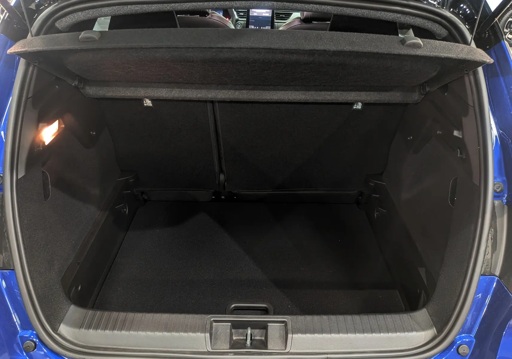 Coffre ouvert vu de l'arrière d'un Renault Captur 2025 Bleu Iron avec toit noir, intérieur noir et éclairage latéral.