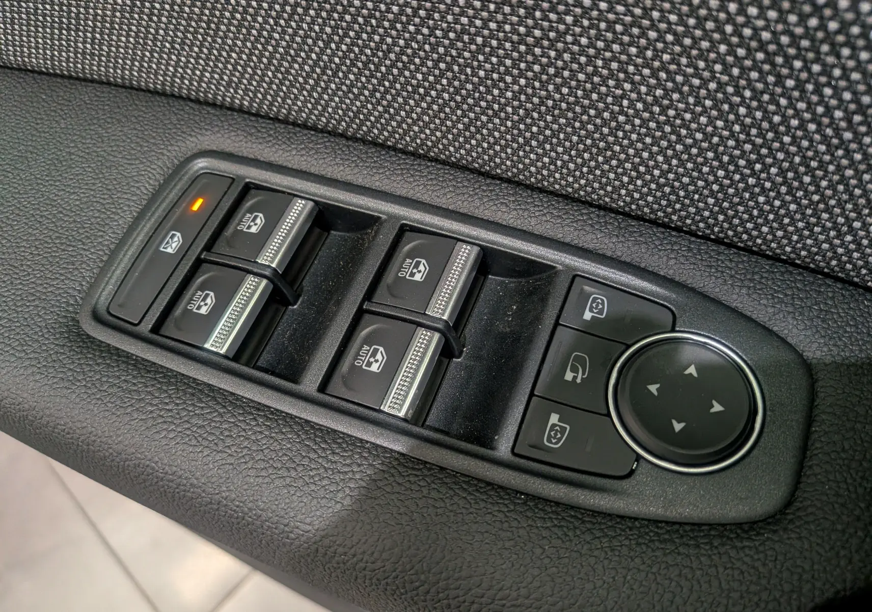 Gros plan sur les commandes des vitres électriques et rétroviseurs du côté gauche d'un Renault Captur 2025 bleu Iron toit noir.