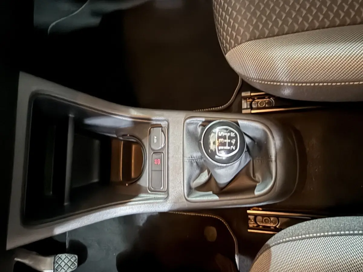 Vue plongeante sur la console centrale du Volkswagen Up 1.0 65 Active gris foncé, mettant en valeur le levier de vitesses manuel et les sièges avant.