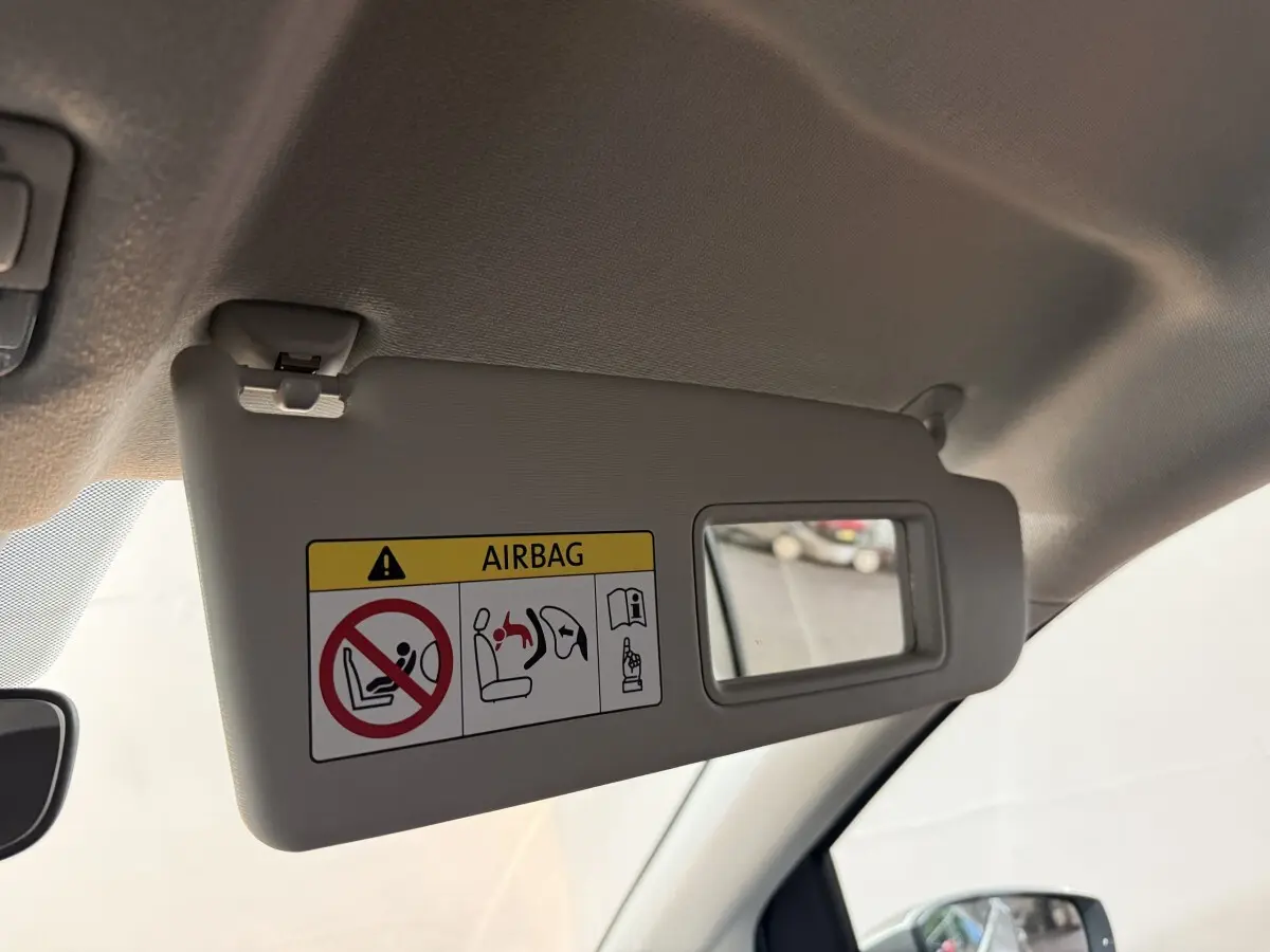 Détail du pare-soleil côté conducteur avec miroir intégré et avertissement airbag dans un Volkswagen Up gris foncé.