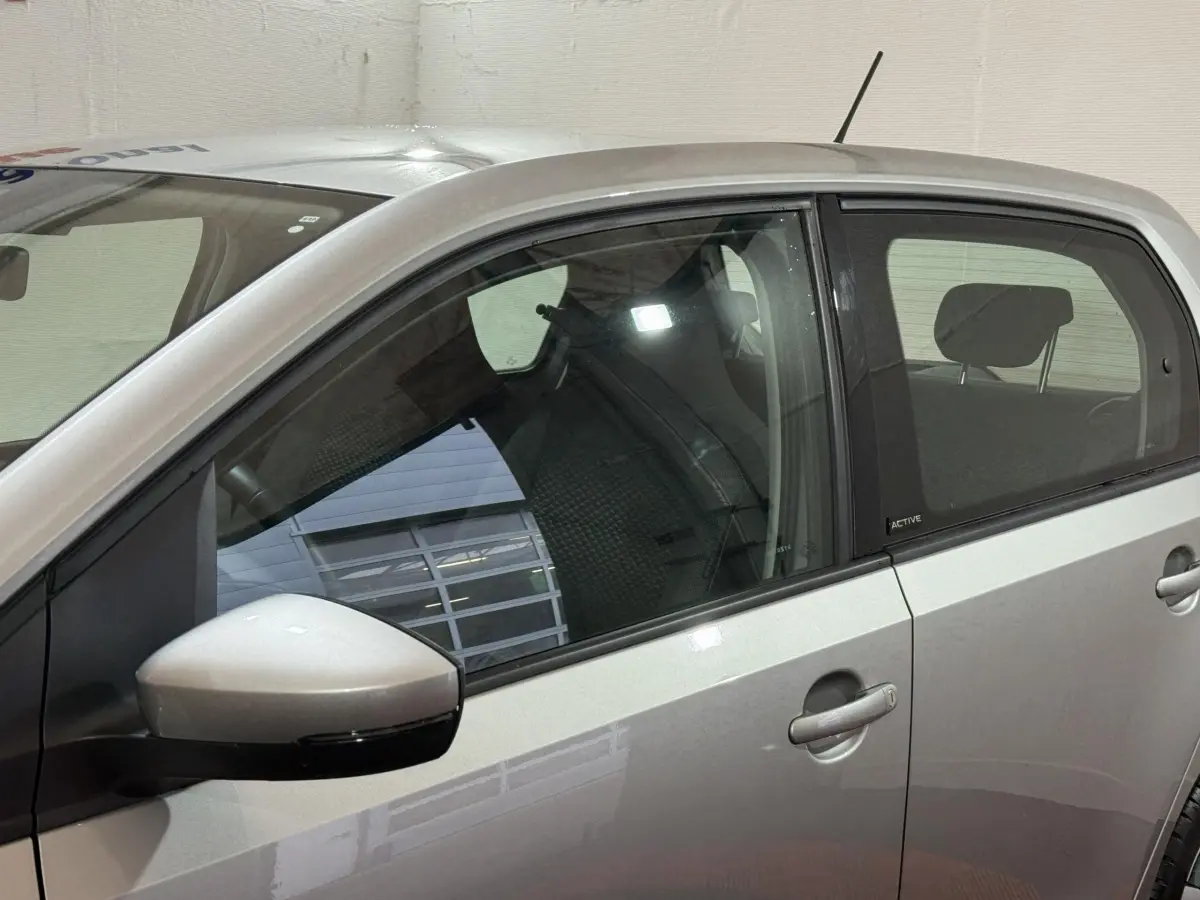 Vue latérale gauche d'une Volkswagen Up gris foncé avec badge Active sur la porte arrière et rétroviseur assorti.