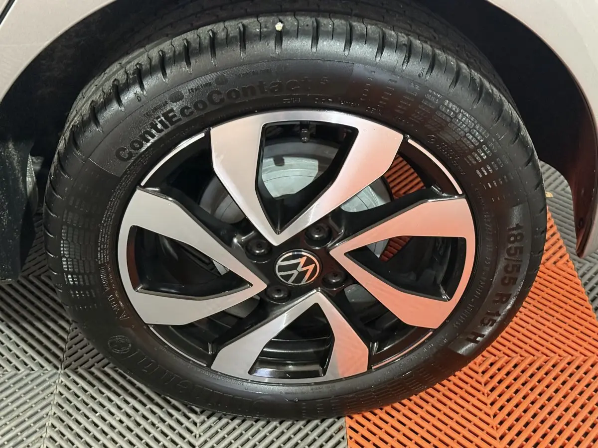 Gros plan sur la jante alliage bicolore noir et argent d'une Volkswagen Up gris foncé, vue côté droit.