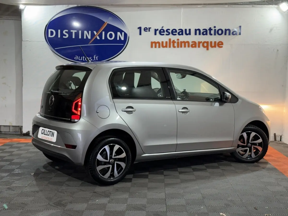 Volkswagen Up 1.0 65 Active gris foncé vue de profil droit en intérieur avec jantes noires et feux arrière LED allumés.