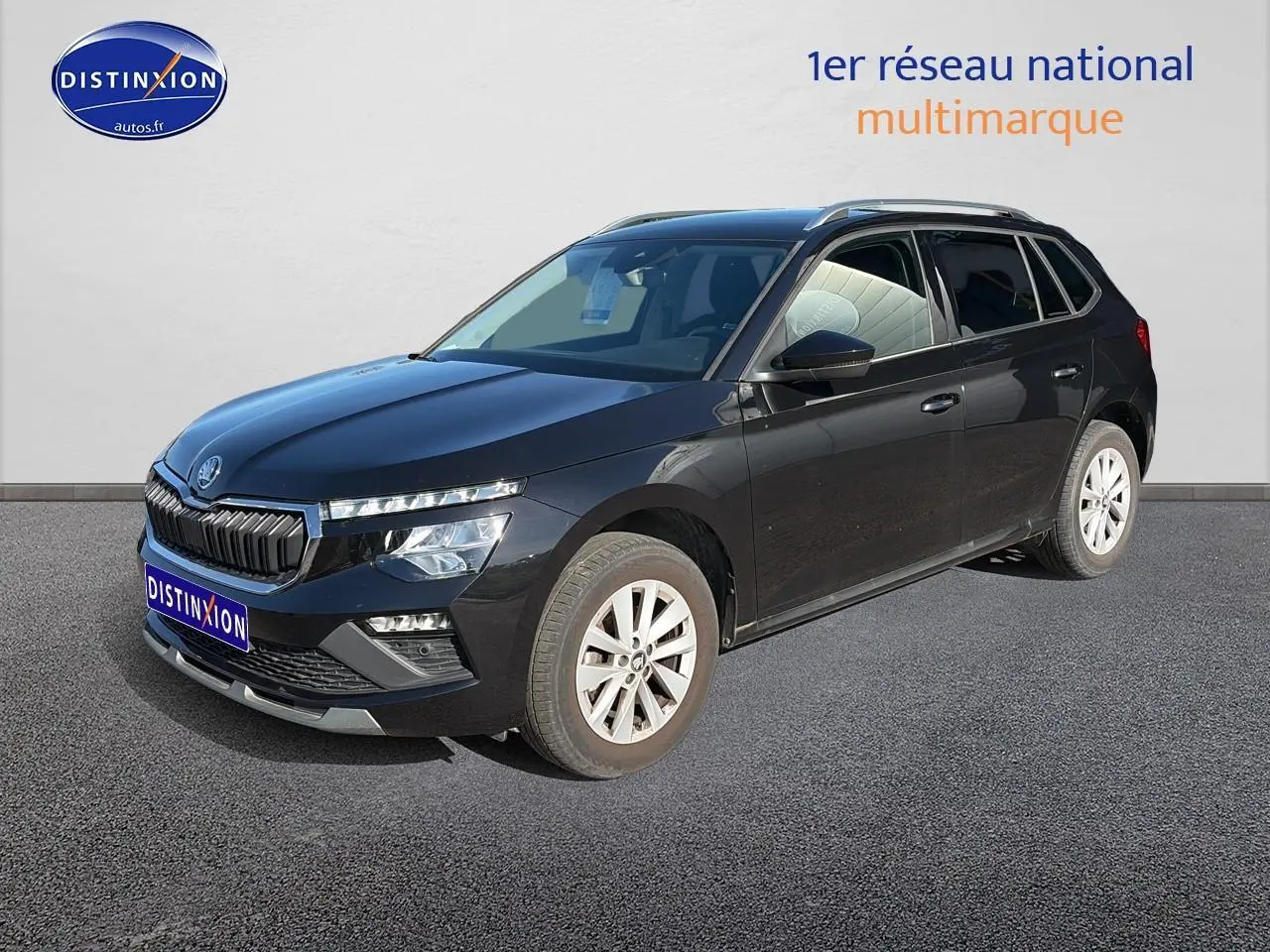 Vue 3/4 avant droit d'un Skoda Kamiq noir avec calandre chromée et jantes alu sur fond neutre.