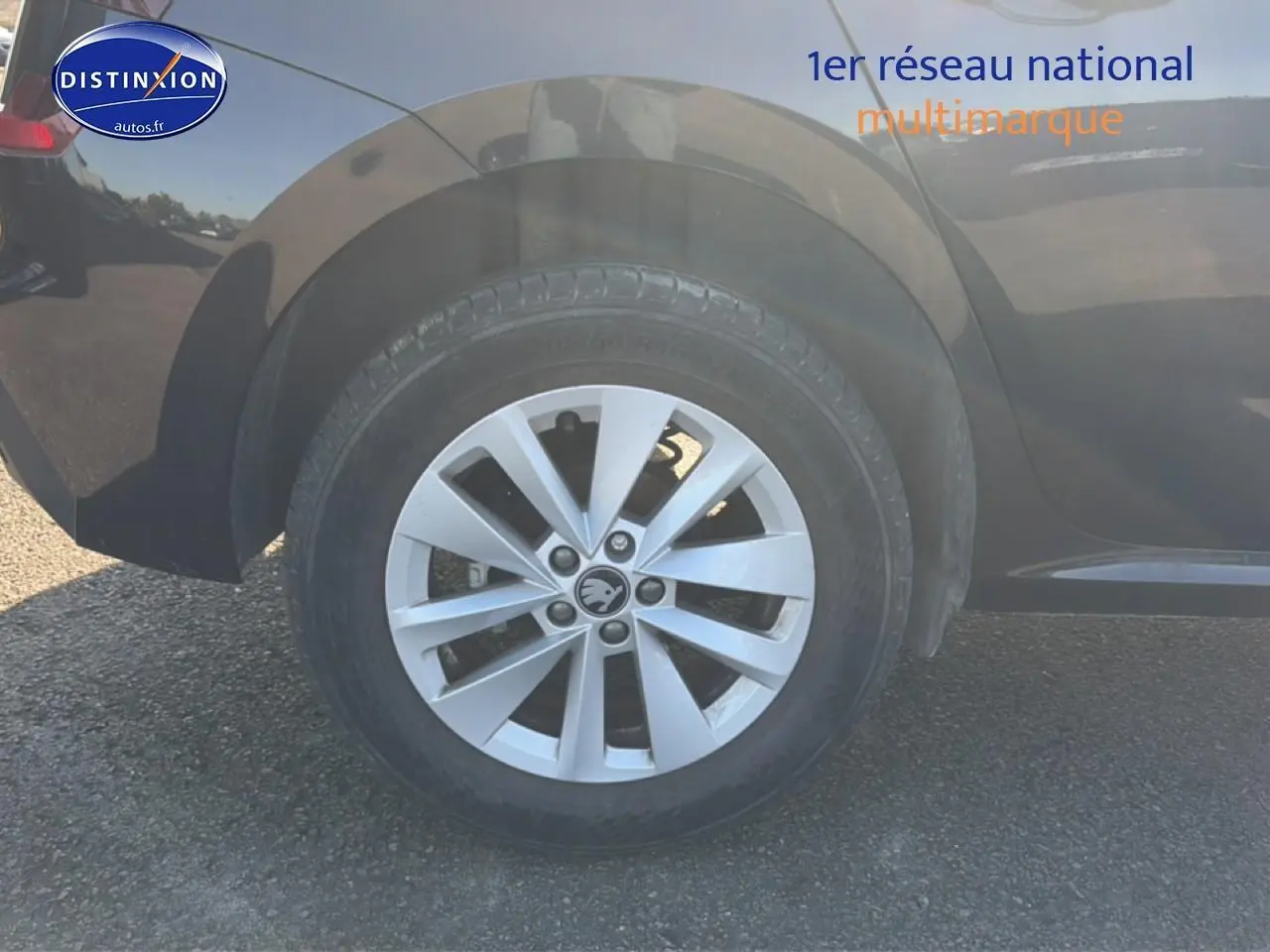 Gros plan sur la roue arrière droite d’un Skoda Kamiq noir avec jante alu et logo au centre.