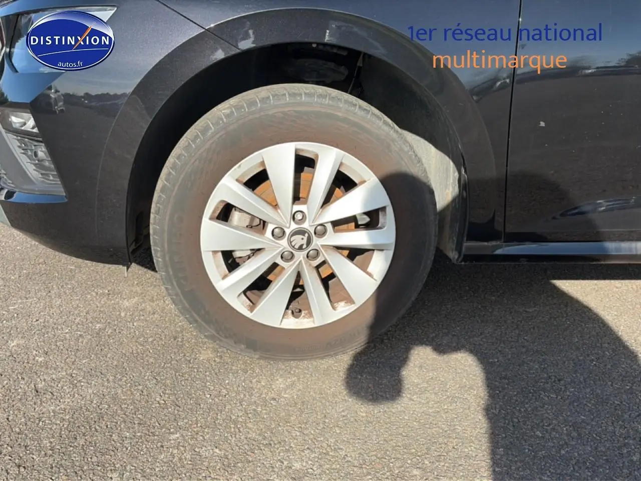 Gros plan sur la roue avant gauche d’un Skoda Kamiq noir, avec jante alu et partie avant du véhicule visible.