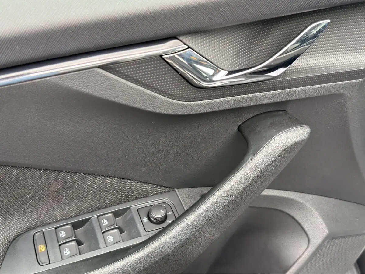 Détail de la porte côté conducteur du Skoda Kamiq gris foncé, avec commandes électriques des vitres et poignée chromée.