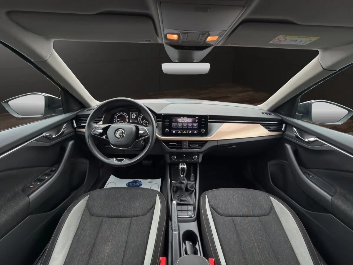 Vue intérieure avant du Skoda Kamiq 2023 gris foncé, avec tableau de bord clair et écran tactile central.