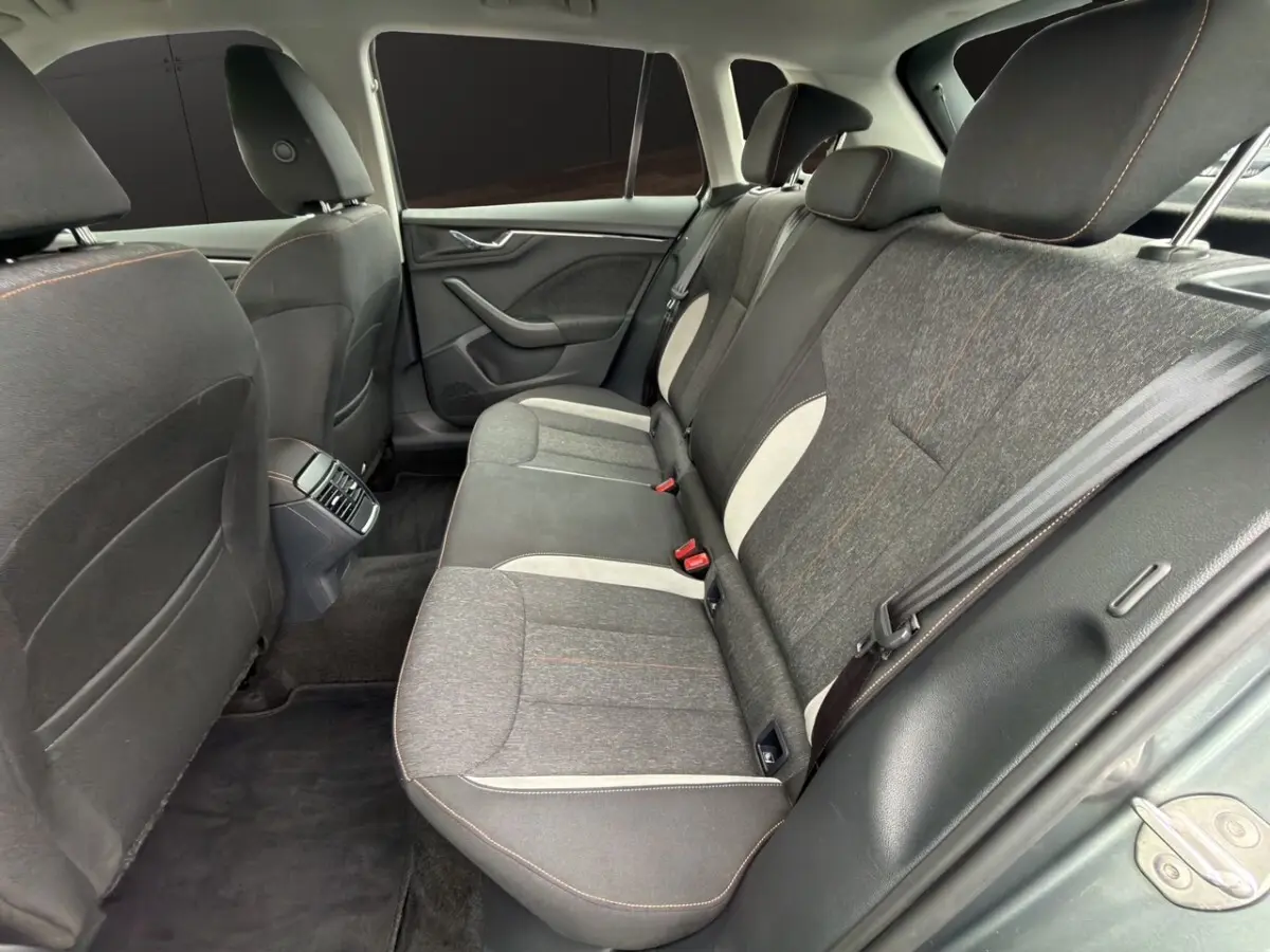 Vue intérieure arrière côté droit du Skoda Kamiq 2023, sièges tissu gris foncé avec surpiqûres orange et inserts clairs.