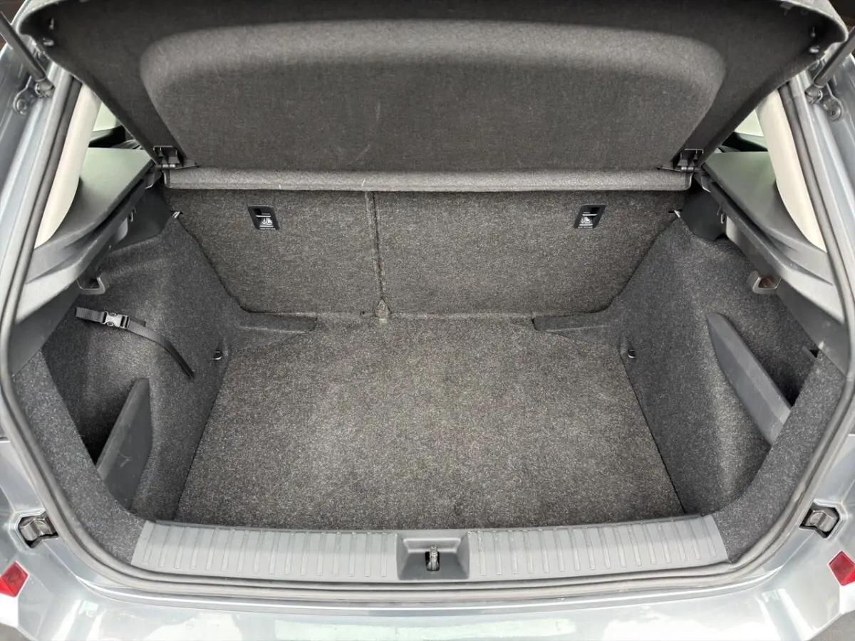 Coffre ouvert vu de l'arrière d'un Skoda Kamiq gris foncé, avec intérieur en tissu gris et espace de rangement vide.