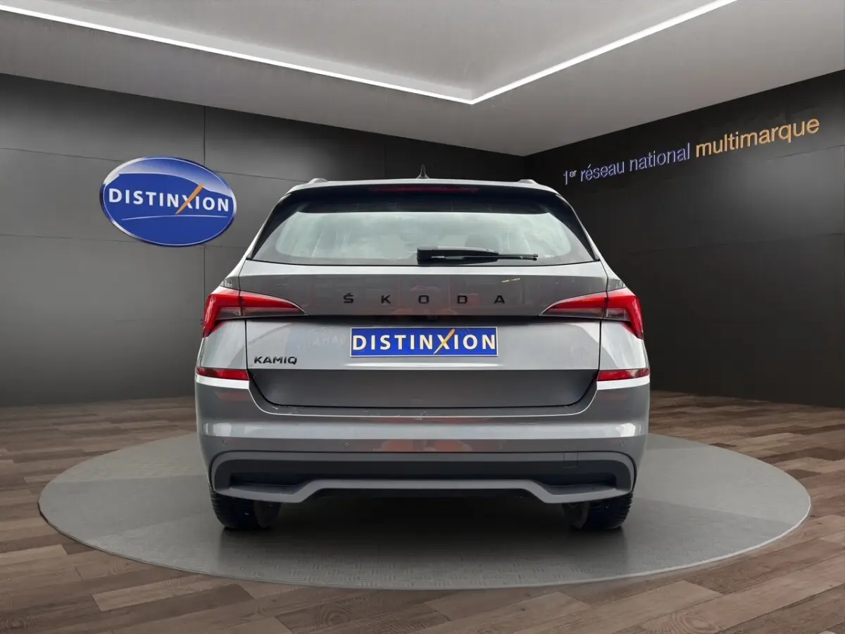 Vue arrière d'un Skoda Kamiq gris foncé avec feux LED et logo distinctif sur fond de showroom.