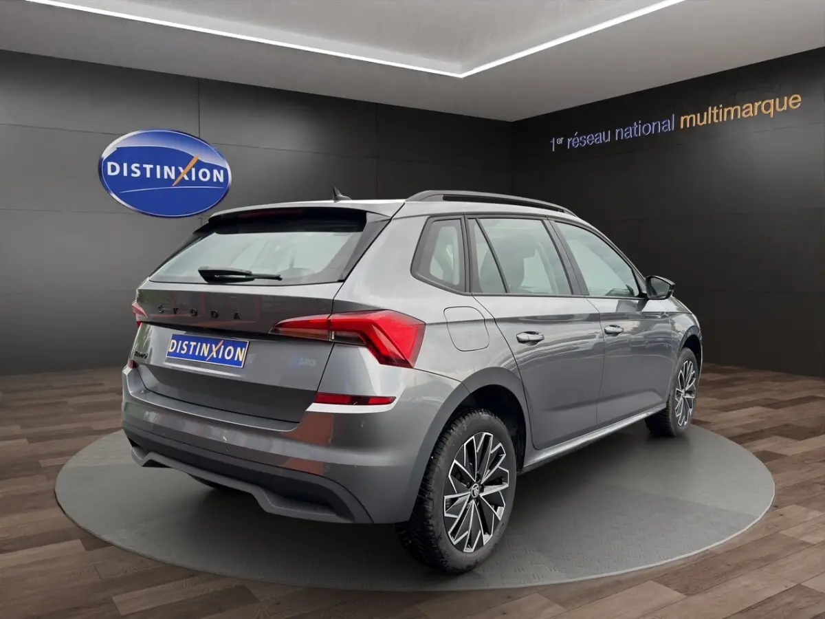 Vue 3/4 arrière droite du Skoda Kamiq gris foncé avec jantes bi-ton et feux arrière LED en showroom.