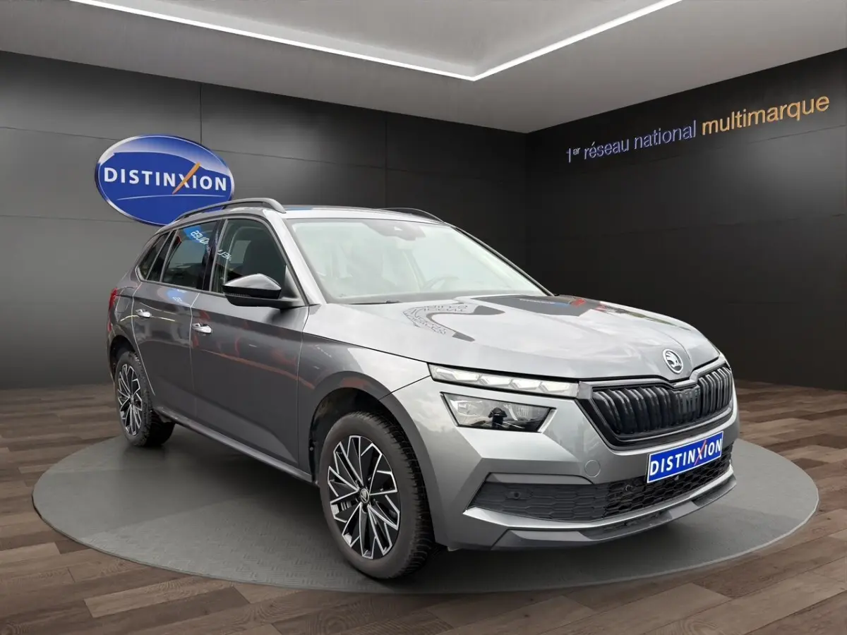 SUV Skoda Kamiq gris foncé vu en 3/4 avant droit avec jantes bi-ton et calandre noire distinctive.