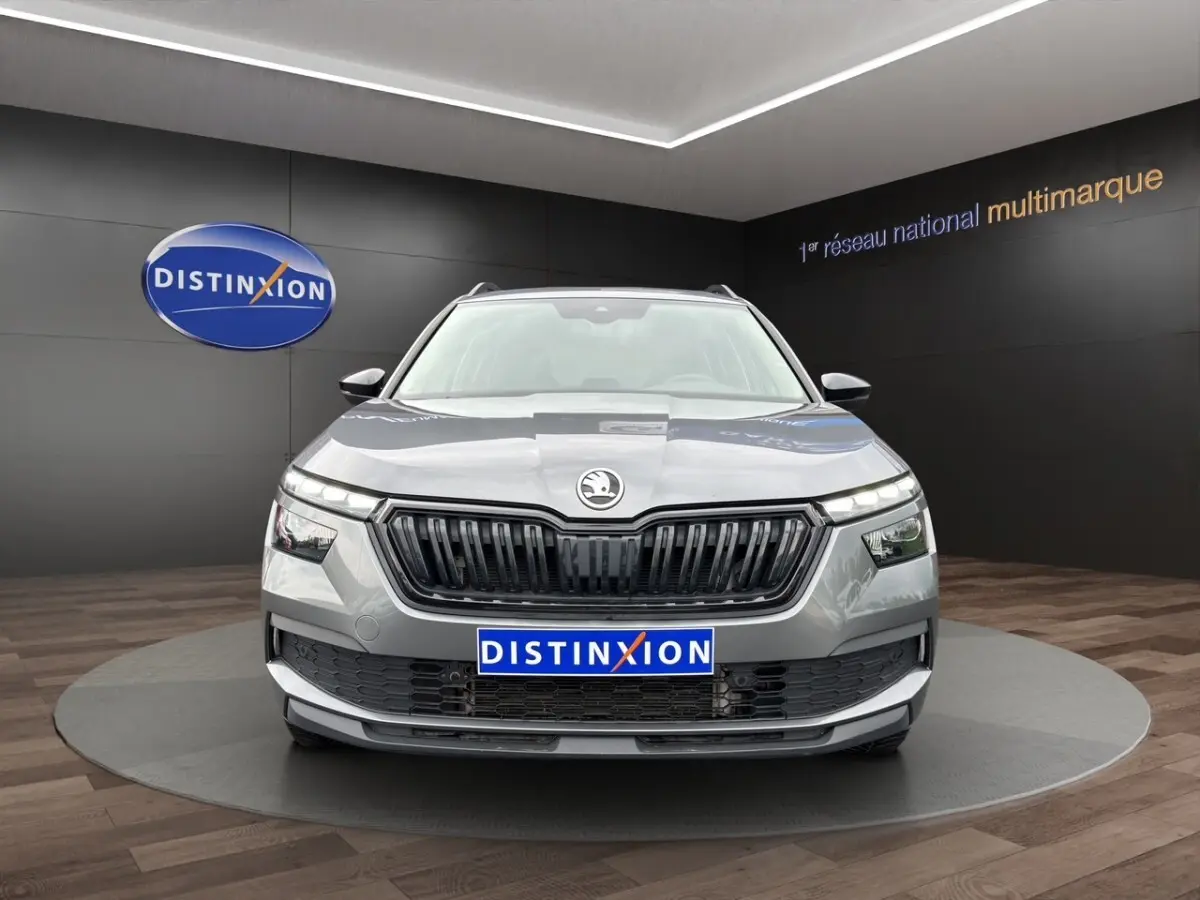 Vue frontale d'un Skoda Kamiq gris foncé avec calandre noire et logo centré, présenté en showroom Distinxion.