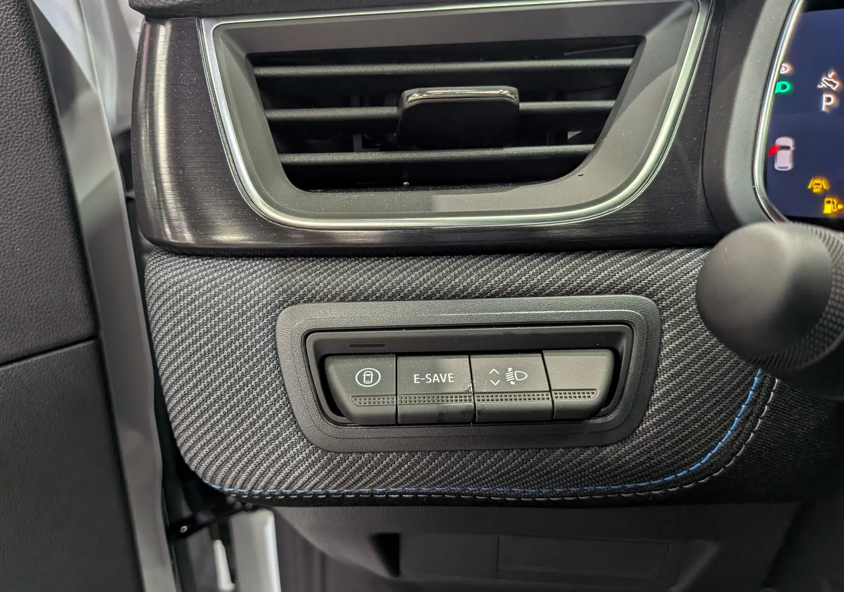 Gros plan sur la console côté conducteur du Renault Captur E-TECH blanc nacré, avec boutons de contrôle et finition carbone.