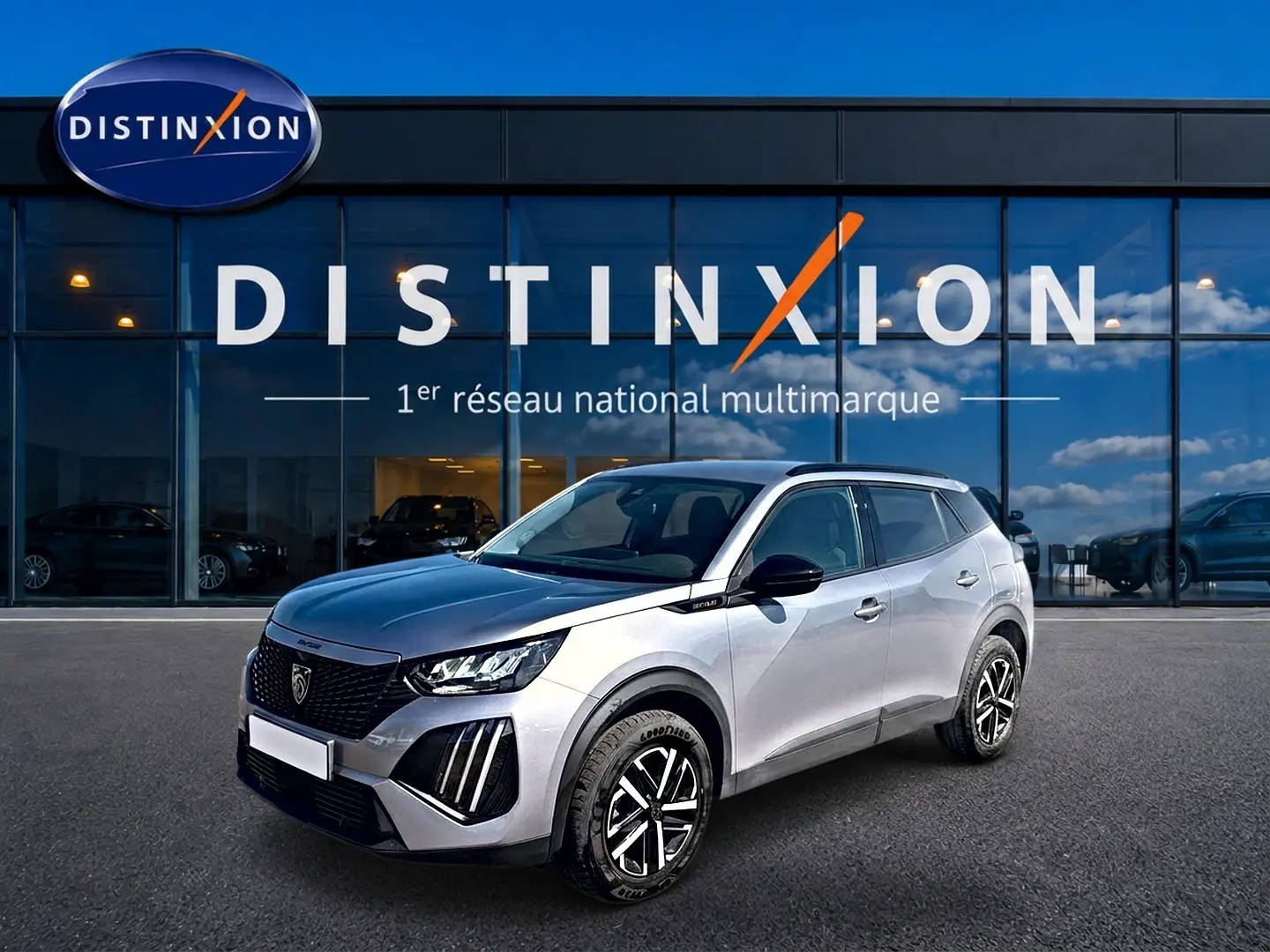 Peugeot 2008 gris 3/4 avant droit, avec calandre noire et jantes distinctives, devant showroom Distinxion.
