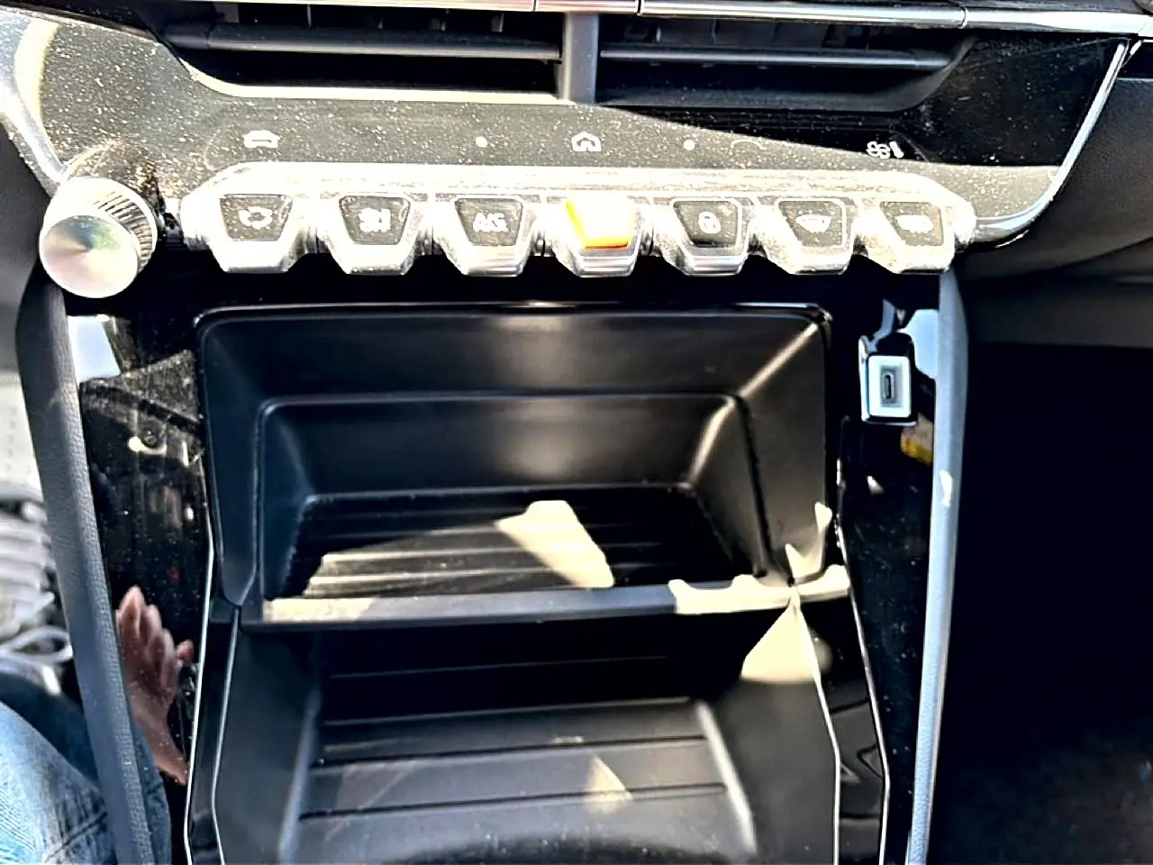Gros plan sur la console centrale noire du Peugeot 2008 1.2 100 style avec rangements et boutons de commande.
